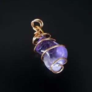 Dije de cristal púrpura enrollado en filamento dorado, hecho a mano por Amarandes, bisutería artesanal Ecuador."