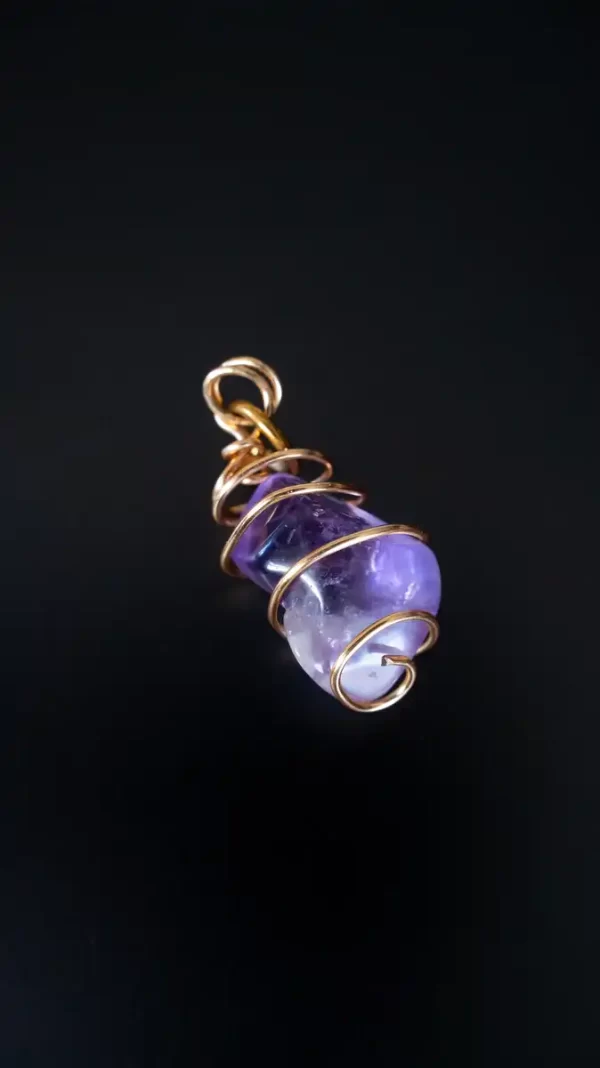 Dije de cristal púrpura enrollado en filamento dorado, hecho a mano por Amarandes, bisutería artesanal Ecuador."