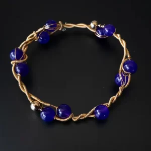 Pulsera dorada con piedras púrpura y diseño inspirado en la naturaleza, elaborada a mano por Amarandes, bisutería artesanal Ecuador.