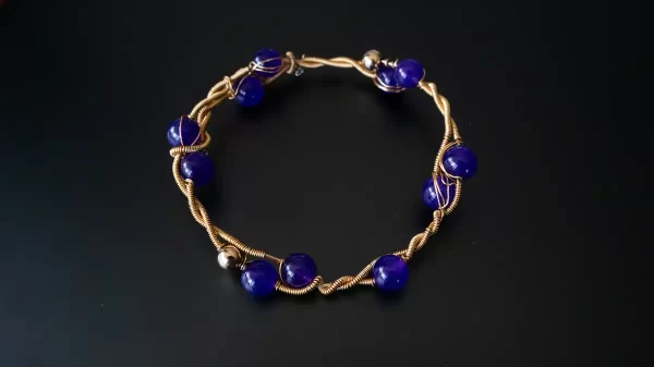 Pulsera dorada con piedras púrpura y diseño inspirado en la naturaleza, elaborada a mano por Amarandes, bisutería artesanal Ecuador.